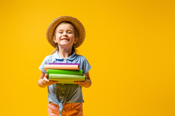 joyful kid in straw hat holding books isolated on yellow