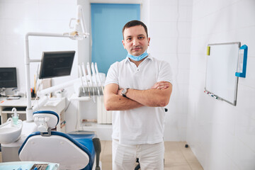 Young handsome dentist looking straight at camera