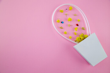 
White paper basket with a scattering of dried flowers of immortelle and yarrow with decorative ladybirds on a pink background. Happy March 8th. Happy Valentine's day. Sale.