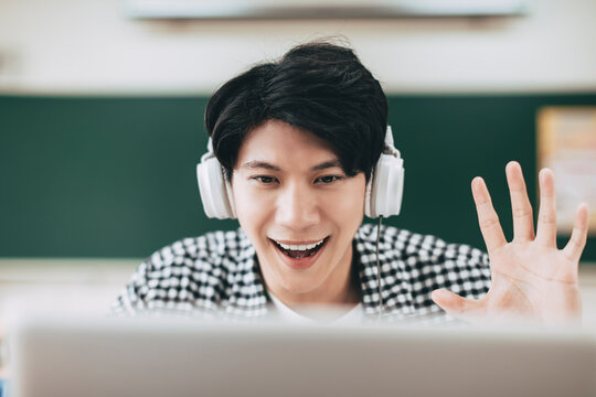 Young Cheerful Asian Student Using Video Call On Laptop In Classroom