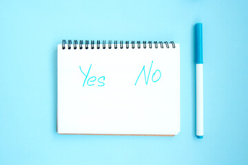 Open notebook with white blank pages on blue background. Notepad with an inscription: Yes No....