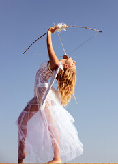 Valentines day. Angel cupid with bow and arrow. Woman in white dress. Portrait of sweet angelic...