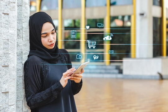 asian muslim woman in black hijab using smartphone, icons digital,