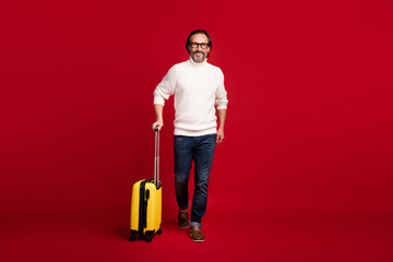 Full length body size photo of aged man going with luggage to airport terminal ready for holidays isolated on red color background
