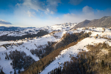 Fototapeta na wymiar Aerial scenic rural view over Pestera village at the bottom of Piatra-Craiului Mountains during a freezing winter in Romania with authentic houses
