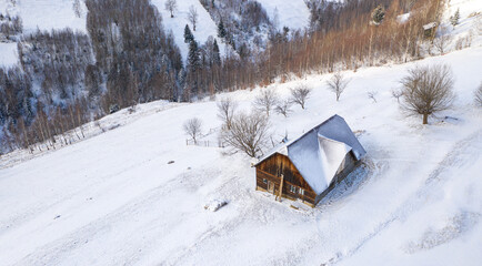 Aerial scenic rural view over Pestera village at the bottom of Piatra-Craiului Mountains during a freezing winter in Romania with authentic houses