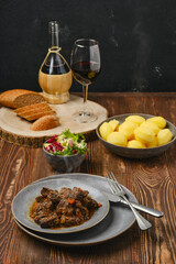 Beef ragout with potato, salad and wine