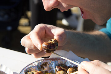 A man eats snails cooked in sauce. Gourmet food.