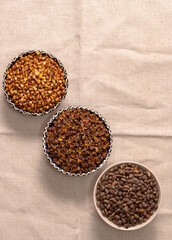 Three round bowls arranged diagonally with Siberian pine nuts. Peeled nut kernels, their shells, whole cone grains.