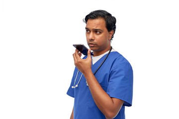 healthcare, medicine and technology concept - indian doctor or male nurse in blue uniform using voice command recorder on smartphone over white background