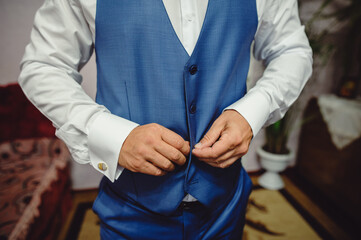 Man is buttoning his vest. close-up. Fashion shot of a handsome young man in elegant classic suit....