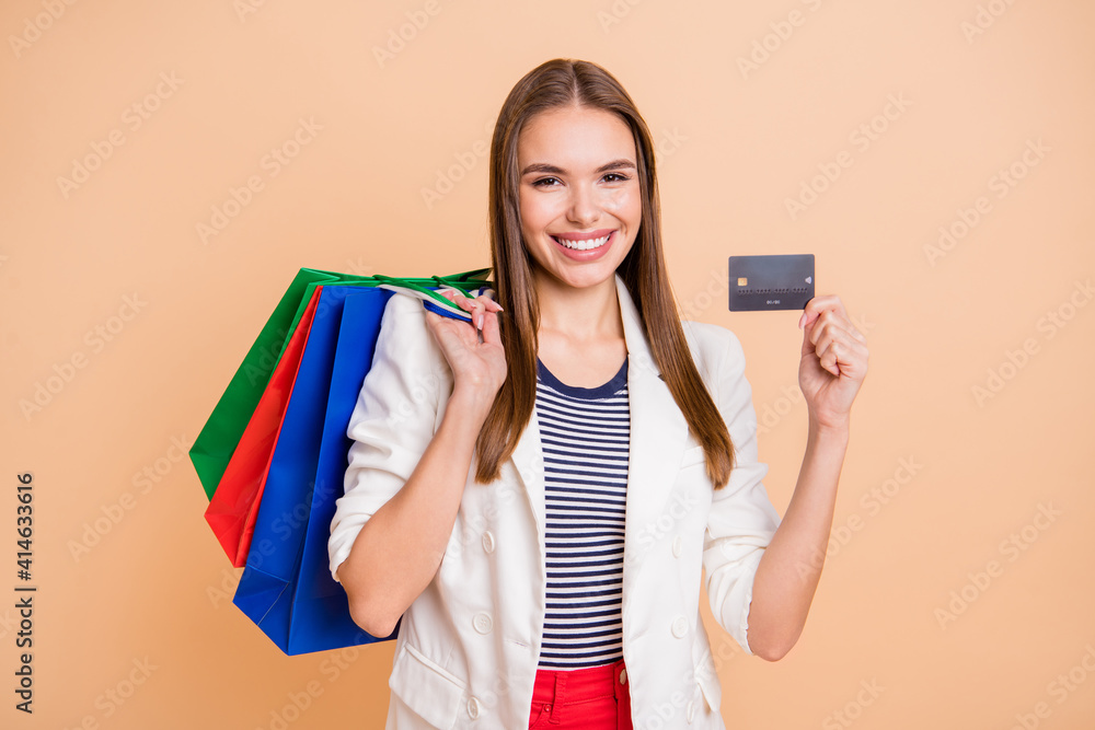 Poster photo of girl hold bags plastic card toothy smile wear white blazer isolated pastel beige color back