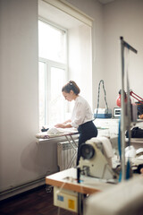 Obraz premium young girl seamstress while working on tailoring in her workshop