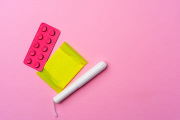 Сontraceptive pills, hygienic pads and tampons on pink background
