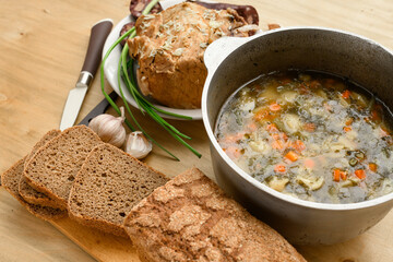baked meat, soup and blood sausage on a plate, green onion and garlic on wooden background, home...