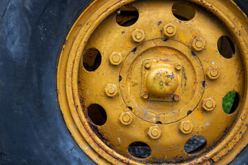 Old yellow wheel with black tire, rustic heavy machine detail photo. Working Tractor or grader detail.