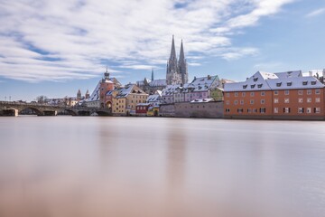 Obraz premium Hochwasser des Flusses Donau im Winter 2021 in Regensburg mit Blick auf den Dom die Altstadt und überschwemmte Promenade und der steinerne Brücke, Deutschland