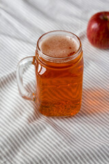 Hard Apple Cider Ale in a Glass Jar Mug on cloth, low angle view.