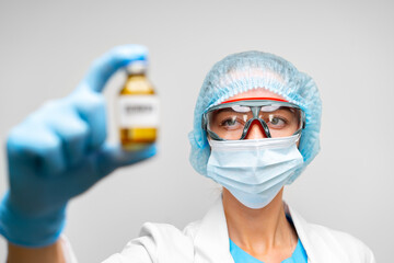 Fototapeta na wymiar Female doctor in protective suit holding vaccine vial