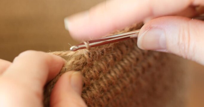 The woman is crocheting from environmentally friendly materials. Jute fiber for home decor. Home hobby of weaving thick-walled rope baskets. Handwork in the interior. Knitted jute and rope baskets.