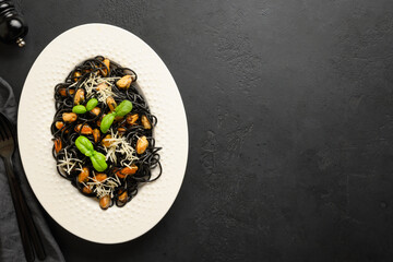 Pasta spaghetti squid Ink with mussels in white plate on black background. View from above.