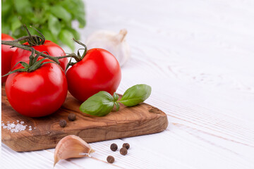 Raw tagliatelle pasta with fresh basil, garlic and tomatoes on a rustic white table, Copy space