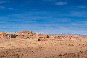 A small traditional village in the Draa-Tafilalet region, with the Atlas Mountains on the background, in Morocco.