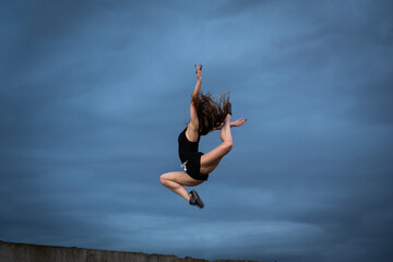 Fototapeta na wymiar Super flexible woman jumping on the sky background. Concept of healthy lifestyle, happiness and joy