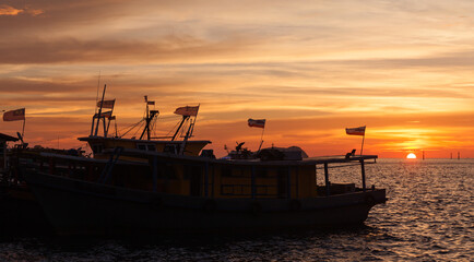 Fototapeta premium Silhouettes of fishing boats with flags, Malaysia