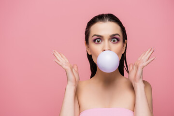 surprised woman with bare shoulders blowing bubblegum isolated on pink