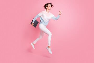 Fototapeta na wymiar Full length photo of shiny sweet young lady dressed pullover jumping holding modern device isolated pink color background