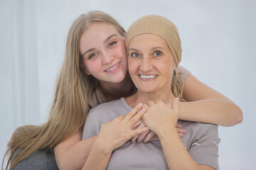 A young and beautiful daughter cuddles her mother's cancer patient and fortifies her to fight during the chemotherapy. Concept for love and support from beloved and family to breast cancer people