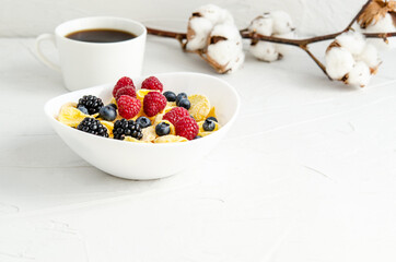 Cornflakes with fresh berries on a plate on a white background.