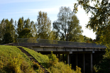 old concrete bridge in the autumn landscape with concrete stairs to access it. blue sky