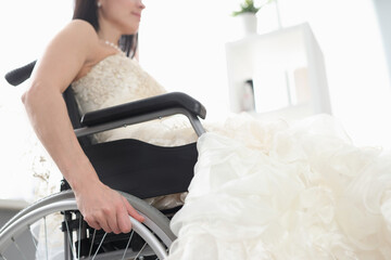 Woman in wedding dress is sitting in wheelchair.