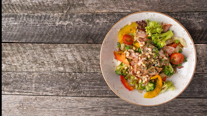 Meat salad with fried bacon, pine nuts and vegetables. Rustic style. Top view, text space