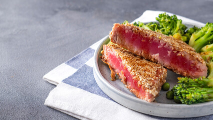 Fried tuna with broccoli and green peas on a plate. Text space