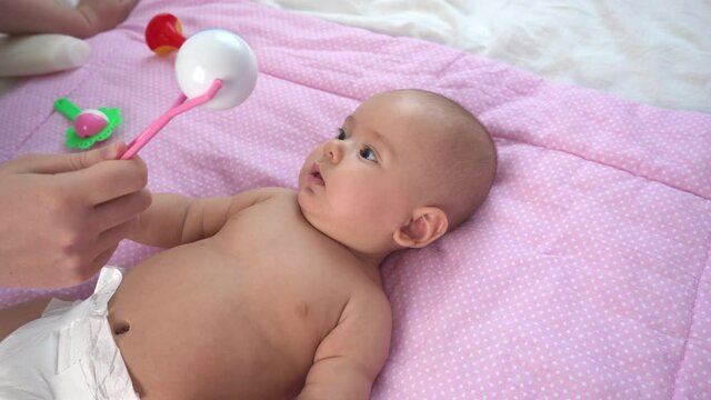 child laughs while playing with a rattle