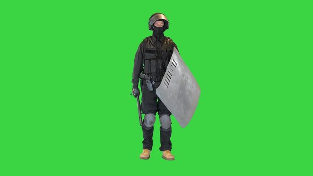 Special unit riot policeman with a shield and baton standing waiting on a Green Screen, Chroma Key.