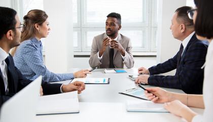 Group of business people sitting around the office desk and discussing the project