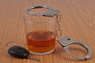 Concept de délit routier avec un verre d'alcool à côté de menottes et de clé de voiture