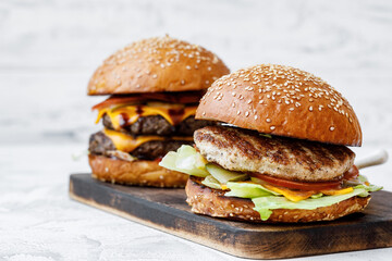 Freshly cooked burger on wooden board on light background