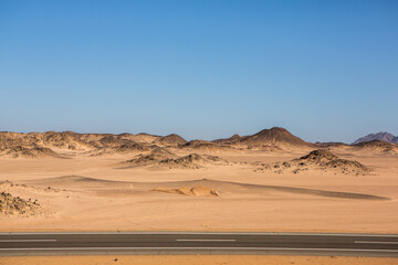 Fototapeta na wymiar Road in the sahara desert of Egypt. Conceptual for freedom, enjoying the journey. Empty road. Freeway, Highway through the desert