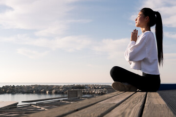 young asian woman sitting meditating by the sea