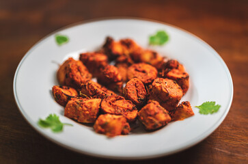 Close up of cooked soy nuggets in a white plate. Dark themed indian vegetarian soya chunks masala, ready to eat finger food with sprinkled seasoning and spices.