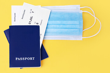 Blue passport, boarding pass, protective medical face mask yellow background close up, travel during coronavirus, covid protection, safety flight, holidays, vacation, international tourism, copy space