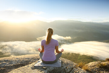 Naklejka na ściany i meble Woman in the top of a cliff meditating doing yoga