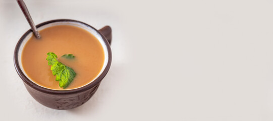 Coffee with cream in a clay mug with a mint leaf on a white background