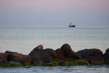 idyllisches Motiv der Nordsee vom Strand aus mit Fischerboot im Hintergrund, blaue Stunde,...