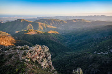 Fototapeta na wymiar Green, hilly and rocky landscape at evening seen from above. Mediterranean landscape in Eastern Spain.